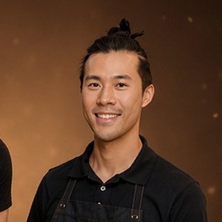James, co-owner of 28 Wishes, smiling in a black 28 Wishes apron, hair in a top knot